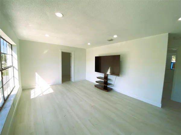 a view of a livingroom with a flat screen tv wooden floor and a way to kitchen