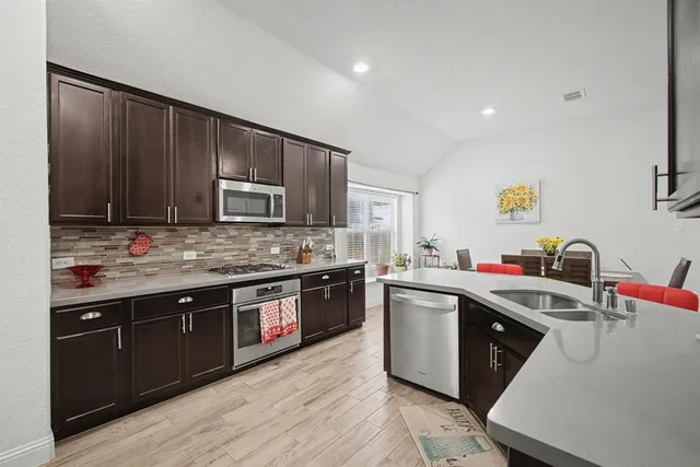 a kitchen with stainless steel appliances granite countertop wooden cabinets a sink dishwasher a stove and a refrigerator