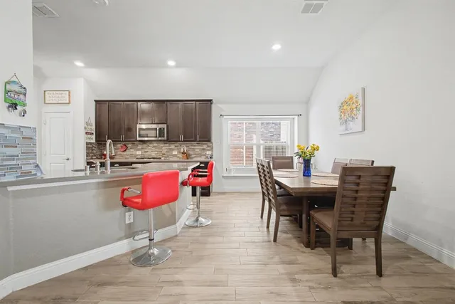 a kitchen with stainless steel appliances kitchen island granite countertop a dining table chairs and granite counter tops