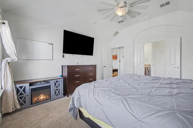 a bedroom with a bed a fireplace and a flat screen tv