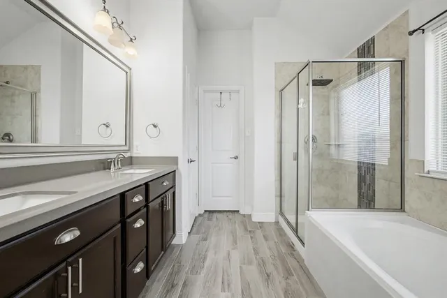 a spacious bathroom with a granite countertop sink a mirror a bathtub and shower