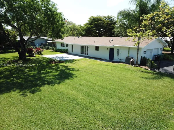 a view of a house with a big yard and large trees