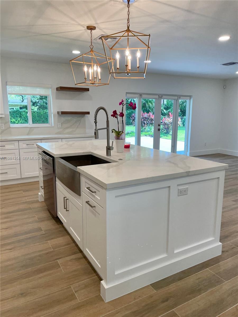 10343 Southwest 114th Street Miami, FL 33176 - Photo 6 of 25 a kitchen with stainless steel appliances granite countertop a sink a stove a dining table and chairs with wooden floor