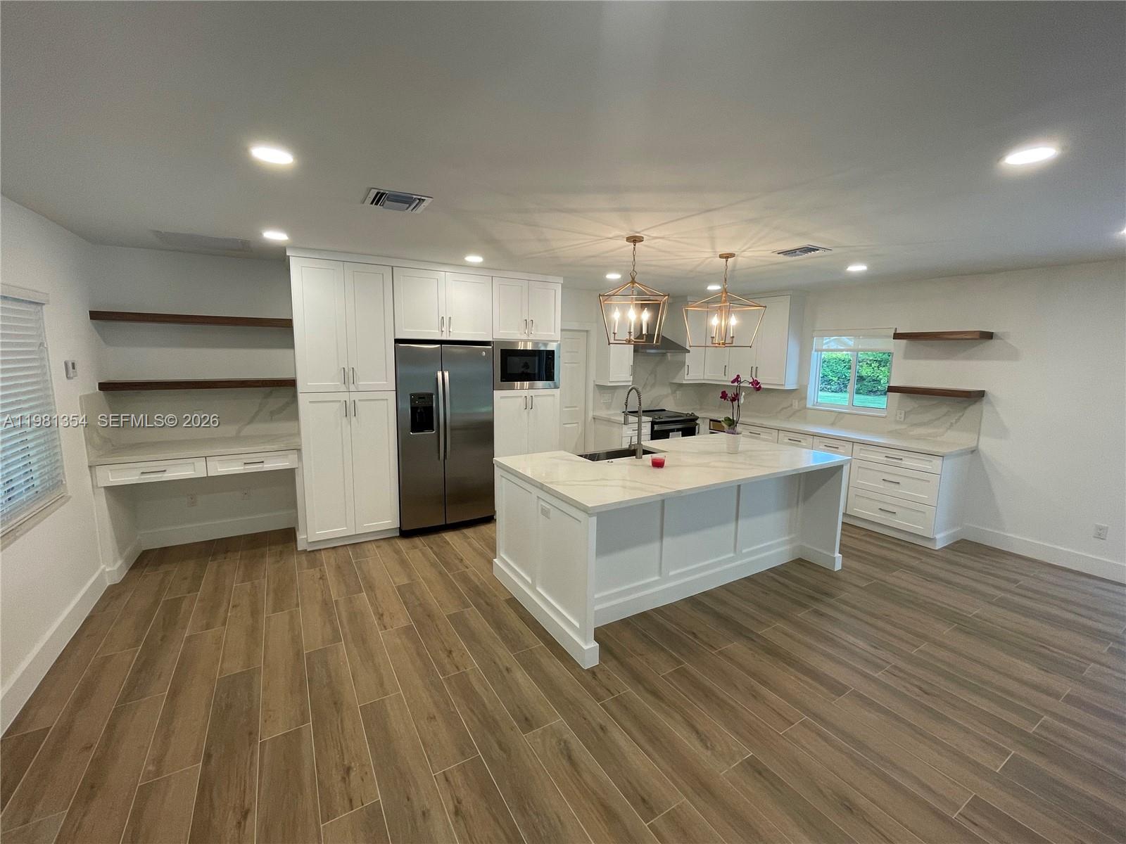 10343 Southwest 114th Street Miami, FL 33176 - Photo 7 of 25 a large white kitchen with kitchen island a sink white cabinets and stainless steel appliances
