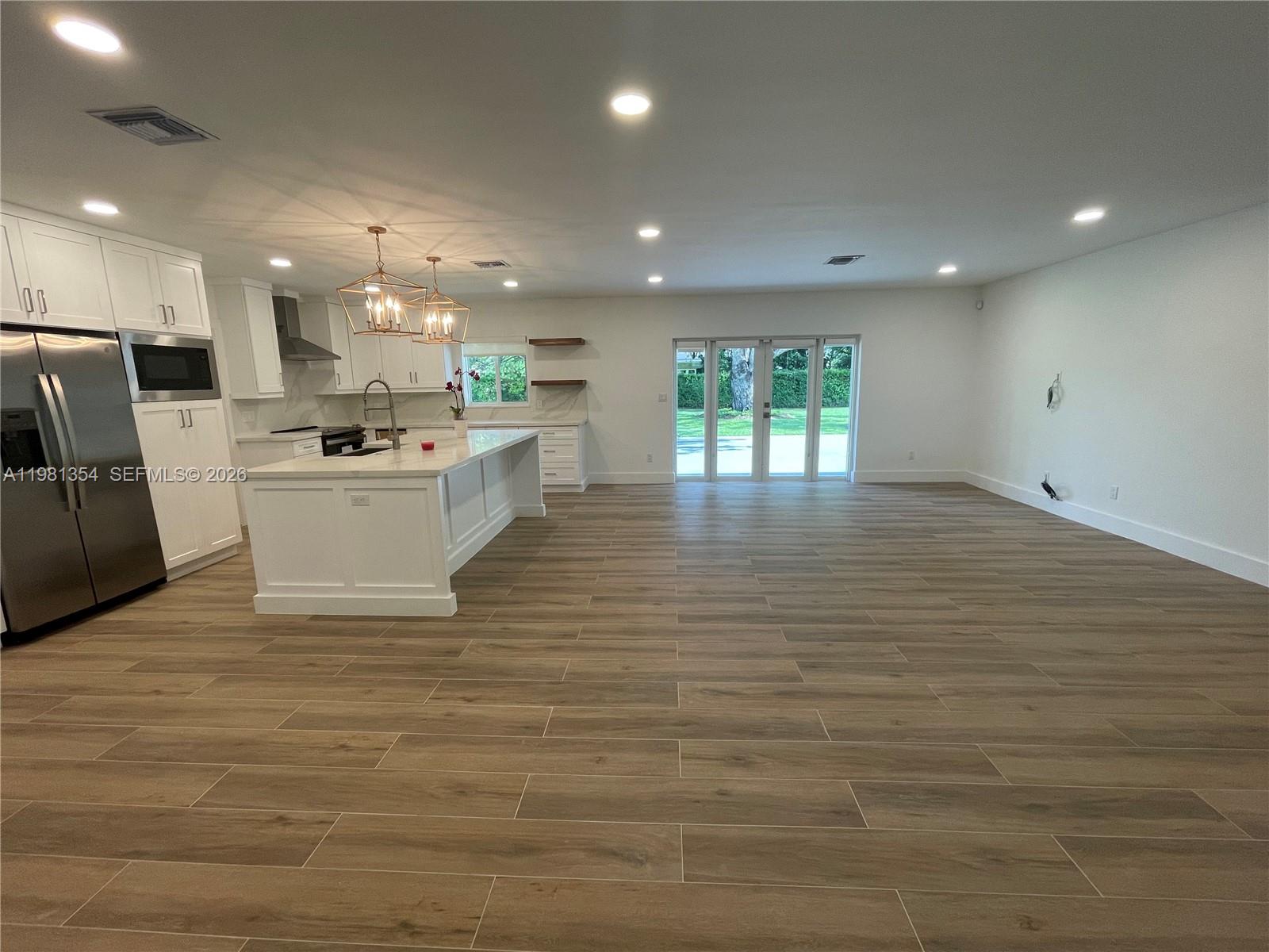 10343 Southwest 114th Street Miami, FL 33176 - Photo 8 of 25 a large white kitchen with kitchen island a sink a stove a refrigerator and a dining table