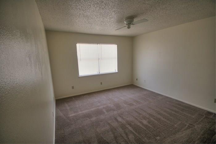 1906 West Loop, Unit D Austin, TX 78758 - Photo 5 of 5 Carpeted room featuring neutral-toned walls, a window with horizontal blinds, and a ceiling fan with integrated lighting