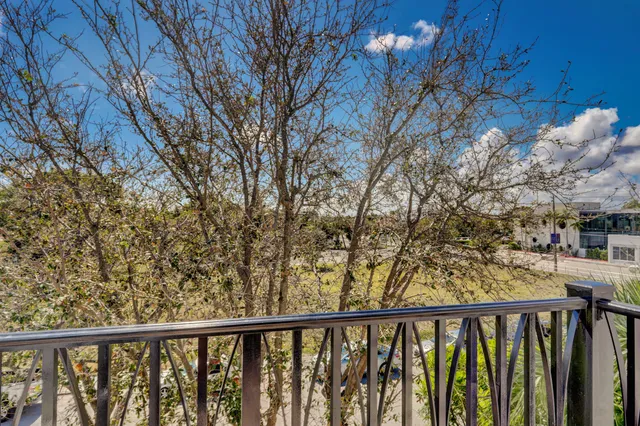 a view of a white house with a yard and palm trees