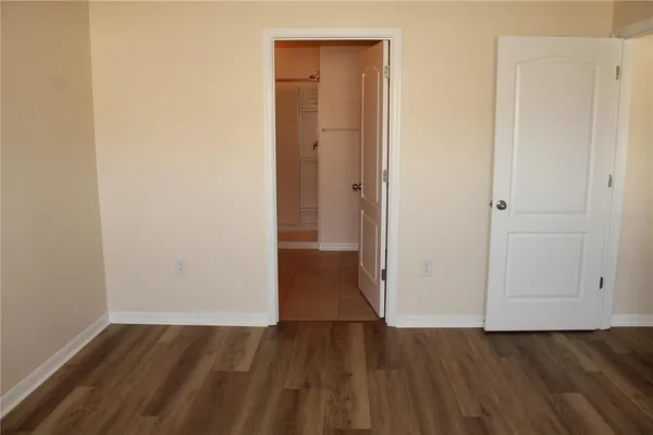 a view of an empty room with wooden floor and closet