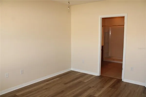a view of an empty room with wooden floor and closet