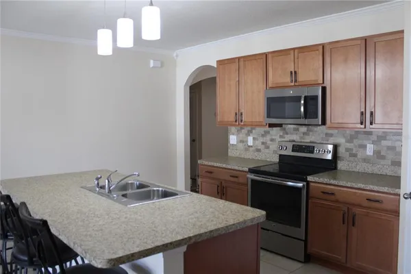 a kitchen with granite countertop wooden cabinets a stove top oven and stainless steel appliances