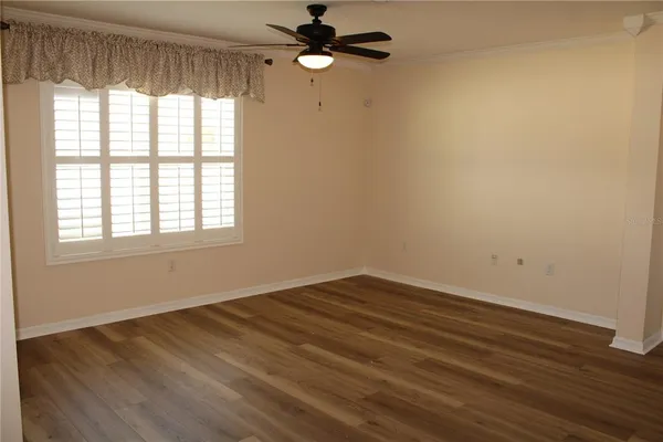 an empty room with wooden floor fan and windows