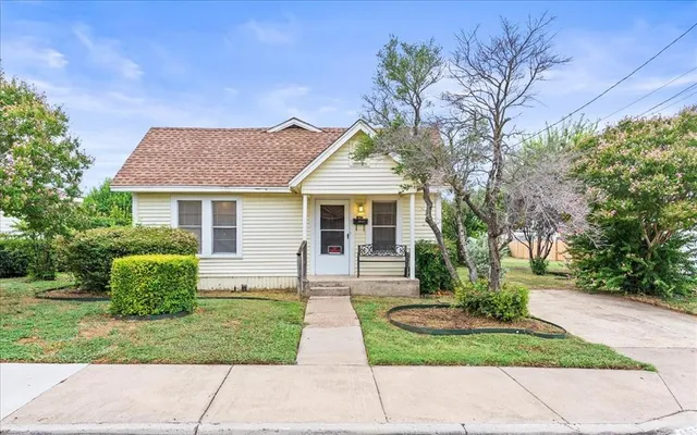 a front view of a house with a yard and potted plants