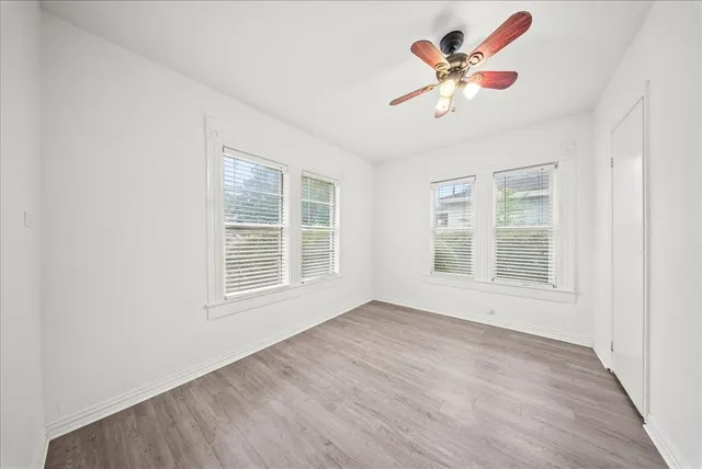 a view of an empty room with a window and wooden floor