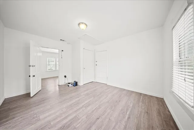 an empty room with wooden floor and windows