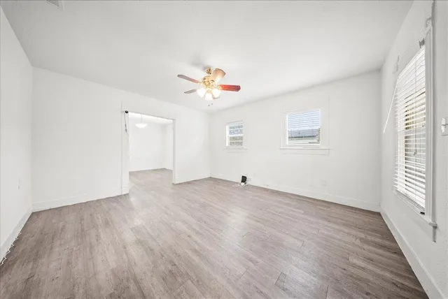 an empty room with wooden floor and ceiling fan
