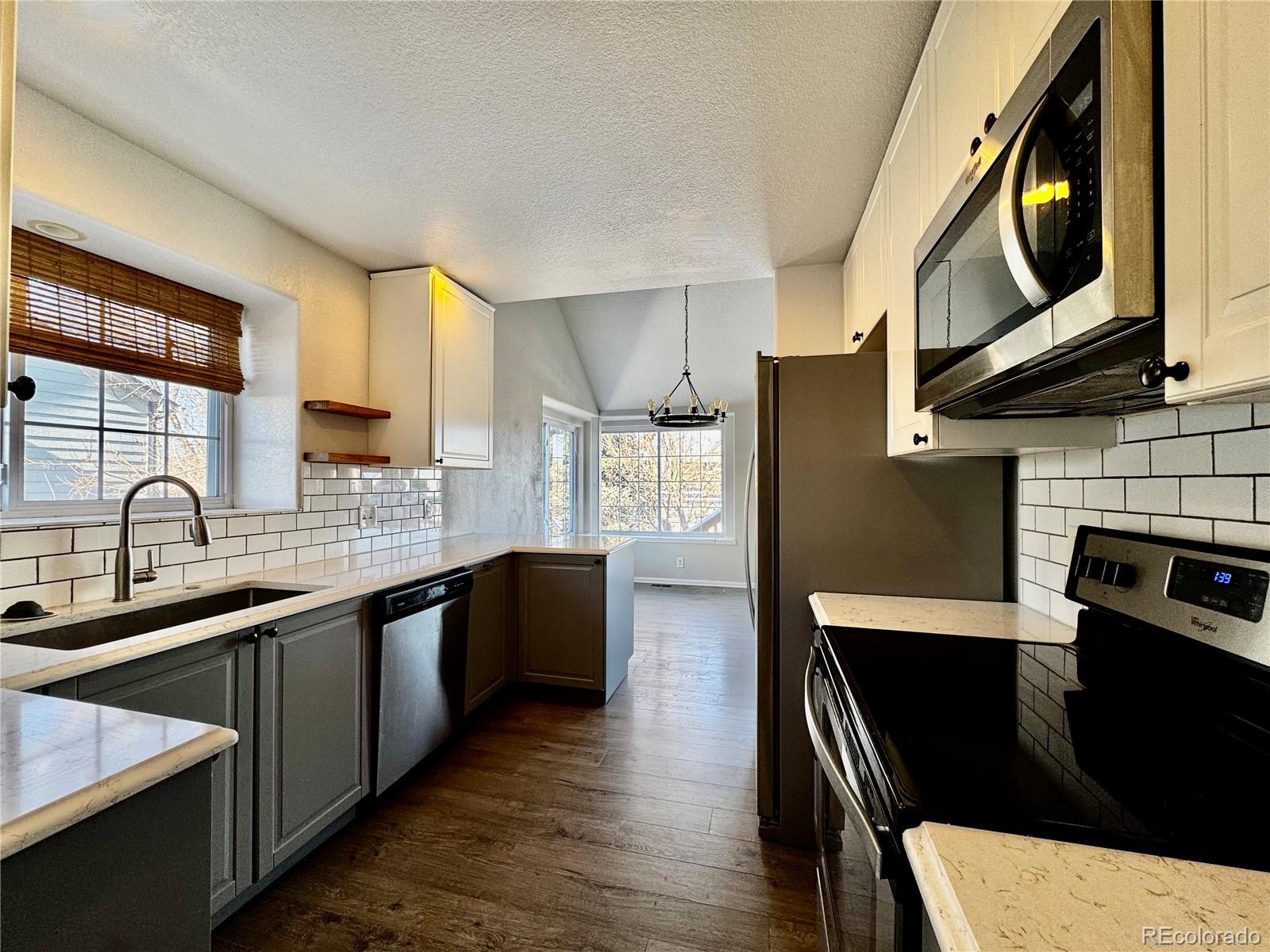 3615 South Flanders Street Aurora, CO 80013 - Photo 5 of 30 a kitchen with stainless steel appliances granite countertop a refrigerator a stove top oven a sink dishwasher and white cabinets with wooden floor