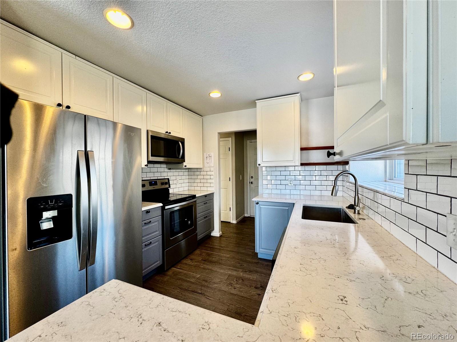 3615 South Flanders Street Aurora, CO 80013 - Photo 6 of 30 a kitchen with granite countertop a refrigerator and a stove top oven