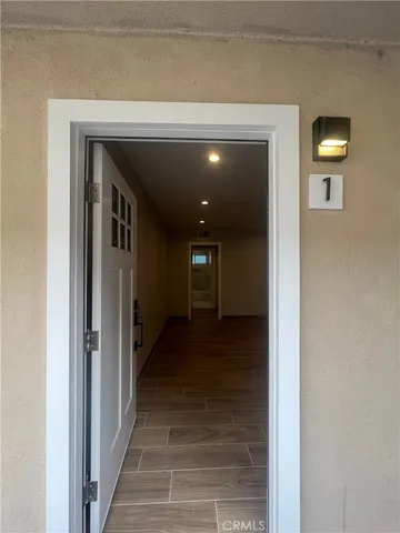 a view of a hallway with wooden floor and a bathroom
