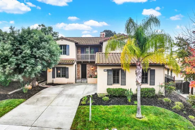 a front view of a house with a yard and potted plants