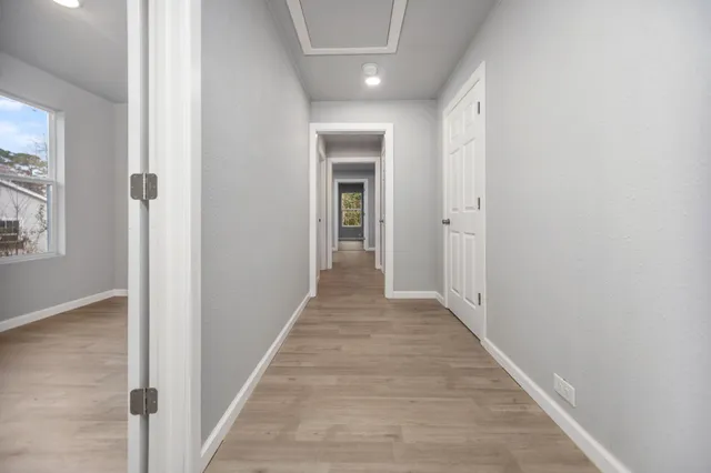 a view of a hallway with wooden floor and a bathroom