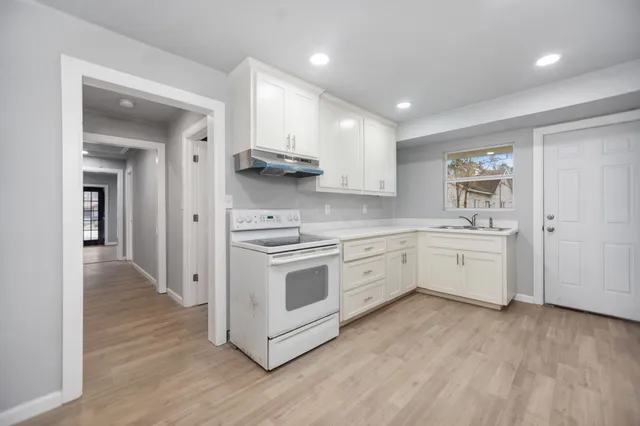 a kitchen with stainless steel appliances a white stove top oven cabinets and a wooden floor