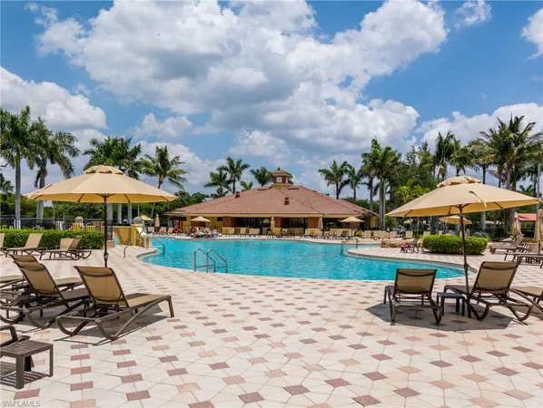a view of a swimming pool with lawn chairs under an umbrella