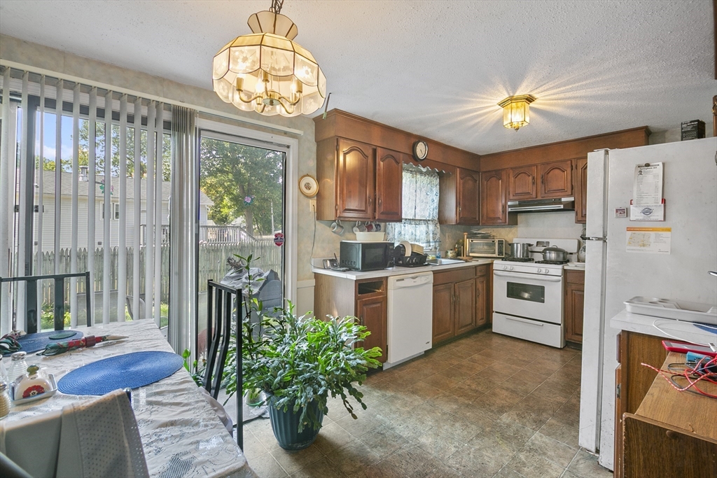 110 Tilton Street Springfield, MA 01109 - Photo 5 of 23 a kitchen with stainless steel appliances a stove a refrigerator and a dining table with wooden floor