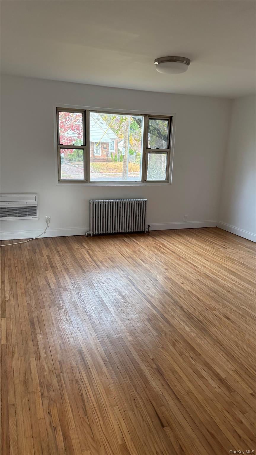1003 Rottkamp Street, Unit 1 Valley Stream, NY 11580 - Photo 6 of 12 a view of an empty room with wooden floor and a window