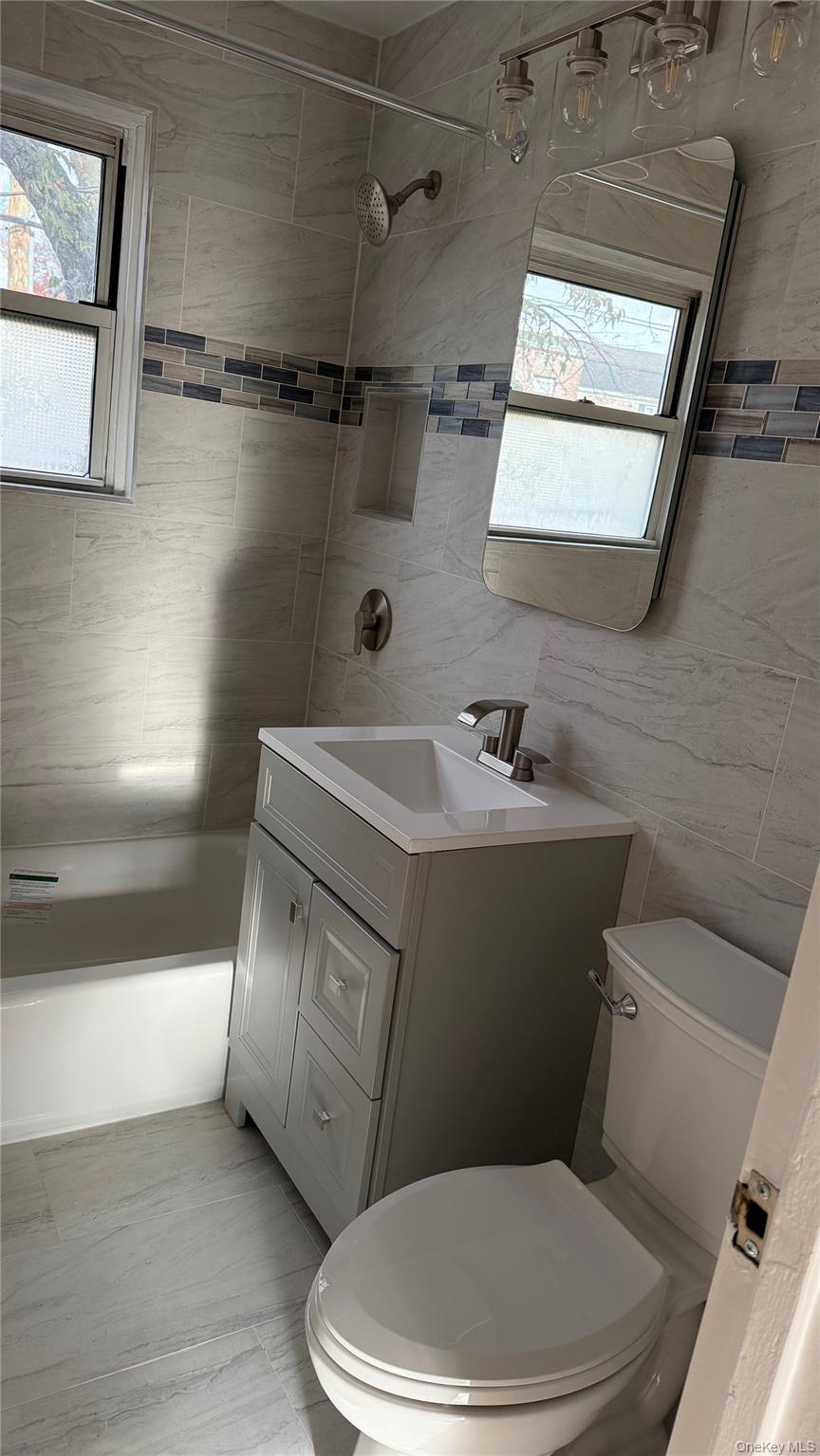 1003 Rottkamp Street, Unit 1 Valley Stream, NY 11580 - Photo 8 of 12 a white toilet sitting next to a bathroom sink