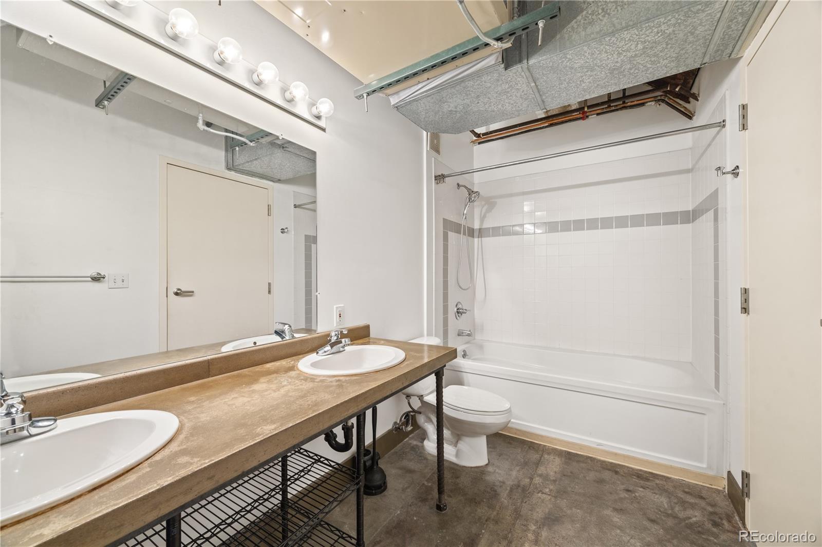 1777 East 39th Avenue, Unit 205 Denver, CO 80205 - Photo 9 of 13 a bathroom with a granite countertop sink a toilet a mirror and shower