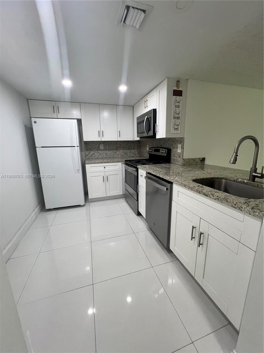 14155 Southwest 87th Street, Unit E201 Miami, FL 33183 - Photo 1 of 14 a kitchen with a sink a microwave and cabinets