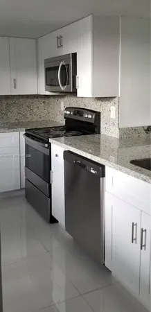 a kitchen with granite countertop a stove top oven microwave and cabinets