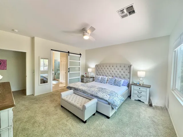 a spacious bedroom with a bed and glass door