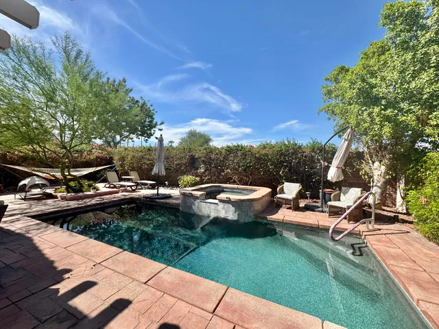 a view of a swimming pool and lounge chairs in back yard of the house