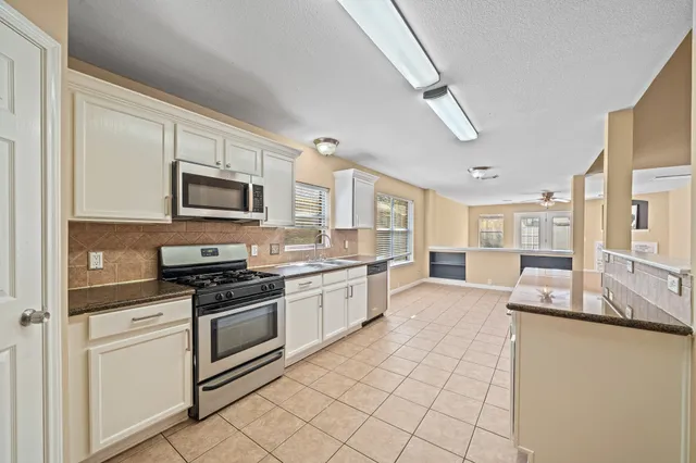 a large kitchen with a stove top oven a sink a counter space and cabinets