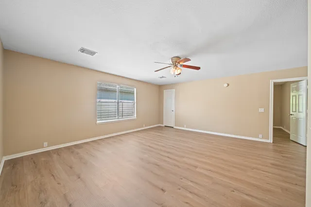 a view of an empty room with wooden floor and a window