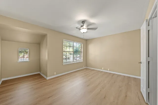 a view of an empty room with a window and wooden floor