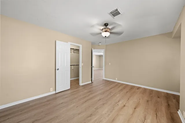 an empty room with wooden floor and ceiling fan