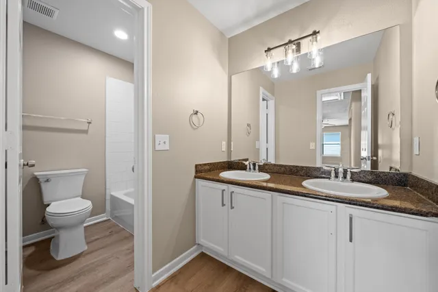 a bathroom with a granite countertop sink a toilet and a mirror