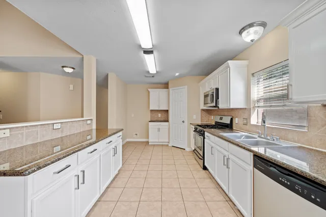 a large kitchen with stainless steel appliances granite countertop a sink and cabinets