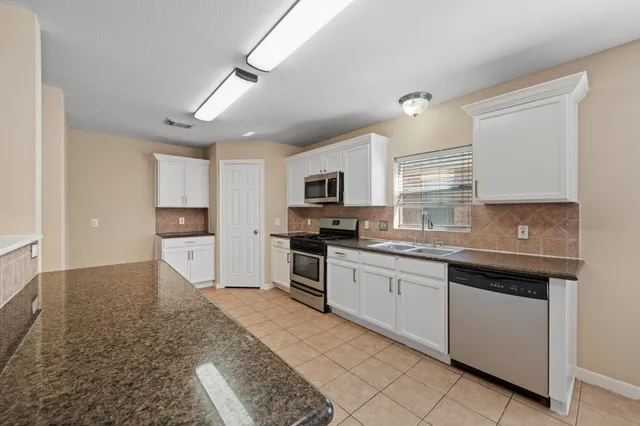 a kitchen with granite countertop stainless steel appliances and white cabinets