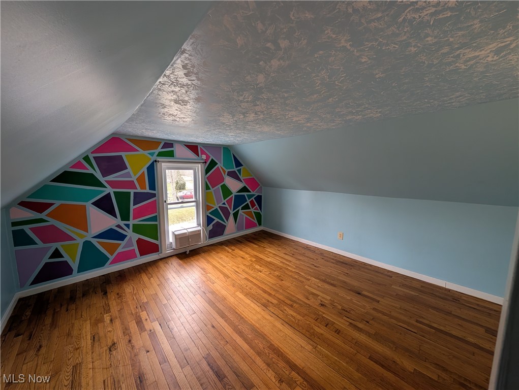 10143 Pleasant Road Pleasant City, OH 43772 - Photo 23 of 32 Additional living space with a textured ceiling, hardwood / wood-style flooring, and vaulted ceiling