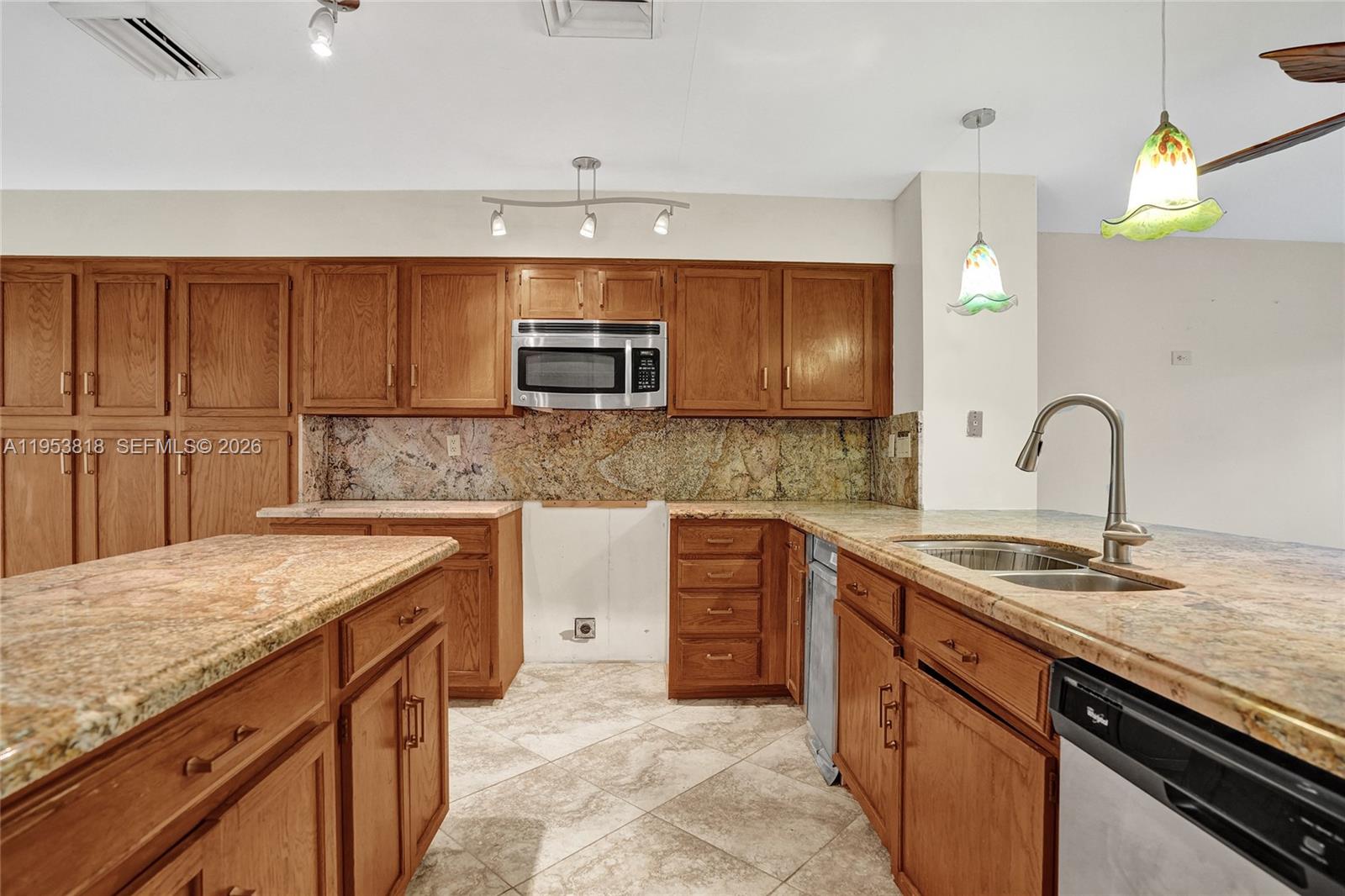 17115 Bay Street Jupiter, FL 33477 - Photo 12 of 73 a kitchen with kitchen island granite countertop a sink stainless steel appliances and cabinets