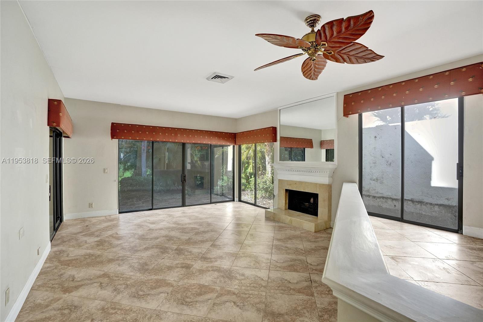 17115 Bay Street Jupiter, FL 33477 - Photo 5 of 73 a view of an empty room with a fireplace and a ceiling fan