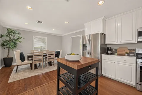 a kitchen with stainless steel appliances a refrigerator a stove a sink dishwasher and a dining table with wooden floor
