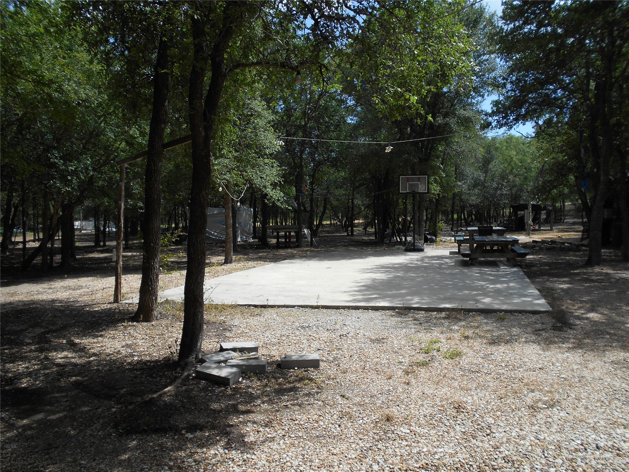 8001 Burleson Manor Road Manor, TX 78653 - Photo 27 of 31 A private basketball court nestled amongst mature trees, ideal for recreational activities.