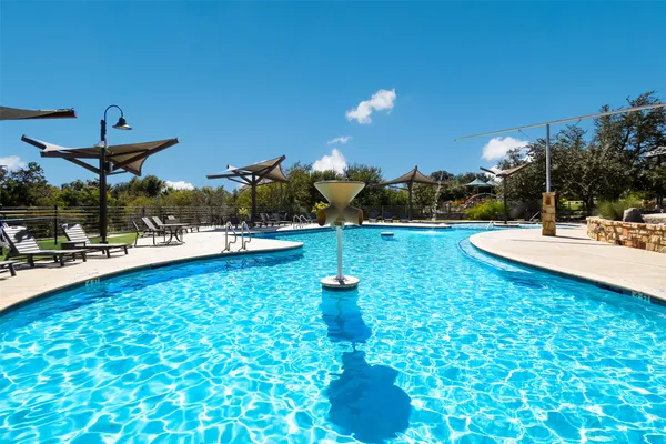 a view of a swimming pool with lawn chairs and plants