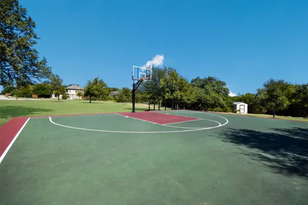 a view of a tennis ground with large trees