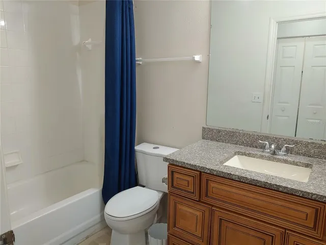 a bathroom with a granite countertop sink a toilet and shower
