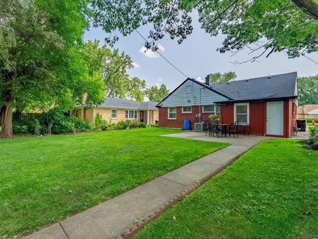 a view of house with a big yard and large trees